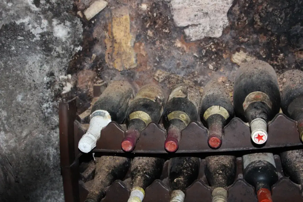 Staubige Flaschen in einem Weinkeller. Die Frage, wie lange kann man Sekt lagern, wird hier durch die lange Lagerung der Flaschen angedeutet.