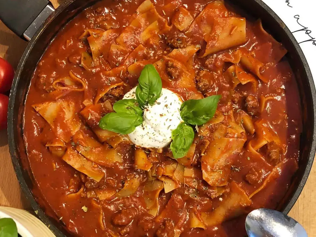 Herzhaftes Lasagnesuppe Rezept in einer Pfanne, garniert mit Basilikum und einem Klecks Ricotta.