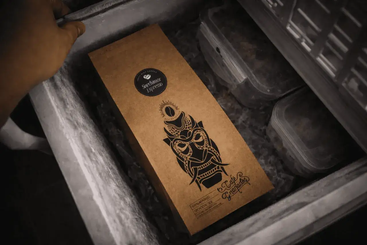Eine Hand legt eine braune Kaffeepackung mit einem Totenkopf-Design in eine Gefriertruhe. Perfekt, um den Kaffee einzufrieren und frisch zu halten.