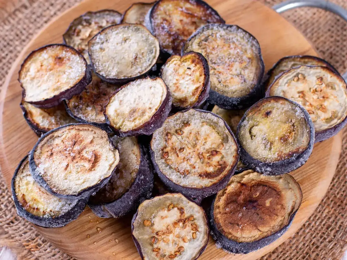 Gefrorene Auberginenscheiben auf einem Holzbrett. Perfekt für die Zubereitung von Gerichten, wenn die Saison vorbei ist. Aubergine einfrieren ist einfach!