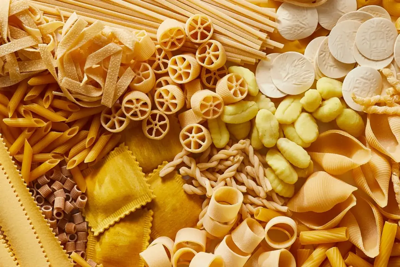 Vielfalt an Nudel-Sorten: Penne, Farfalle, Ravioli, Gnocchi und mehr, arrangiert zu einem köstlichen Mosaik.