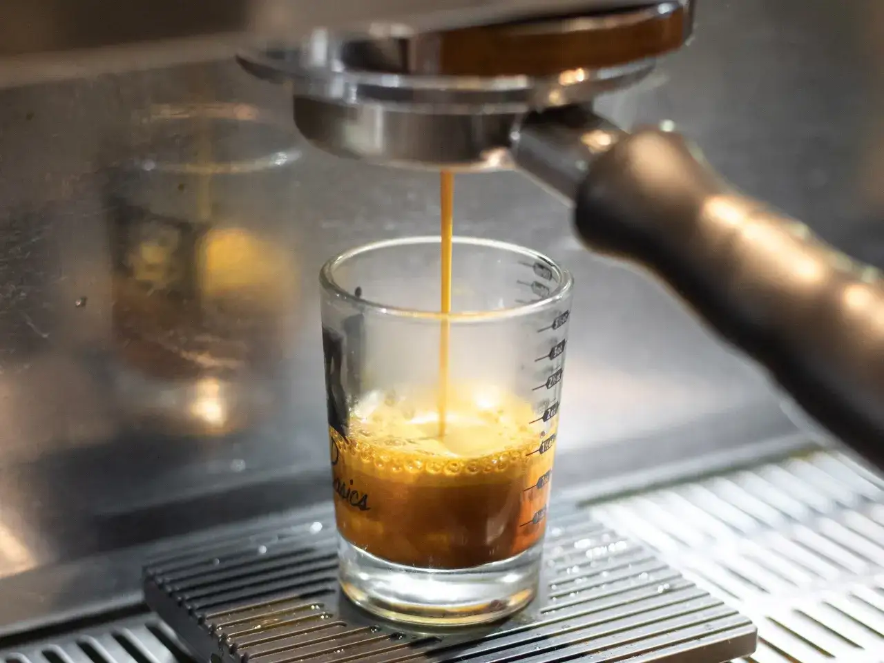 Ein Espresso fließt in ein Glas. Die Crema bildet sich, ein Zeichen für die perfekte Zubereitung.