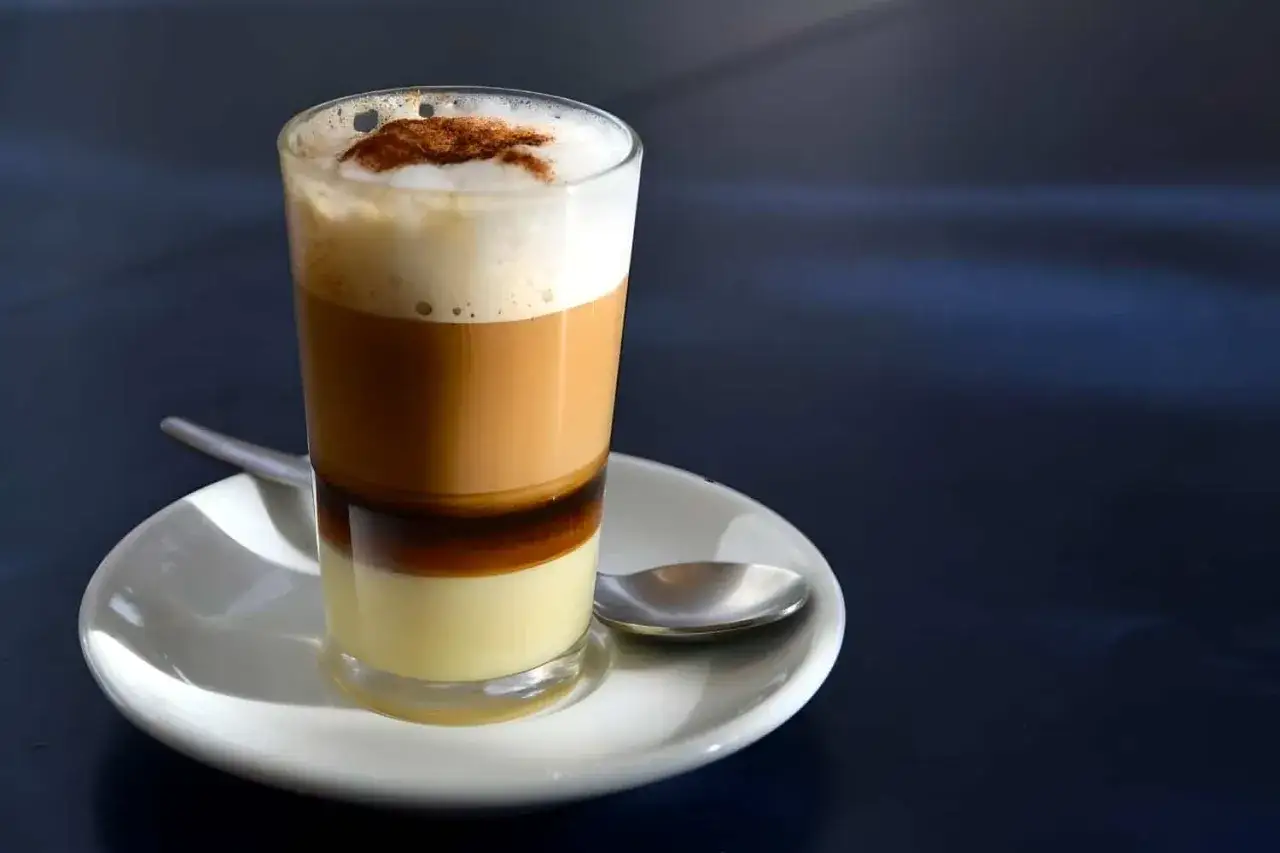 Ein geschichteter Kaffee mit Kondensmilch, Schaum und Zimt.