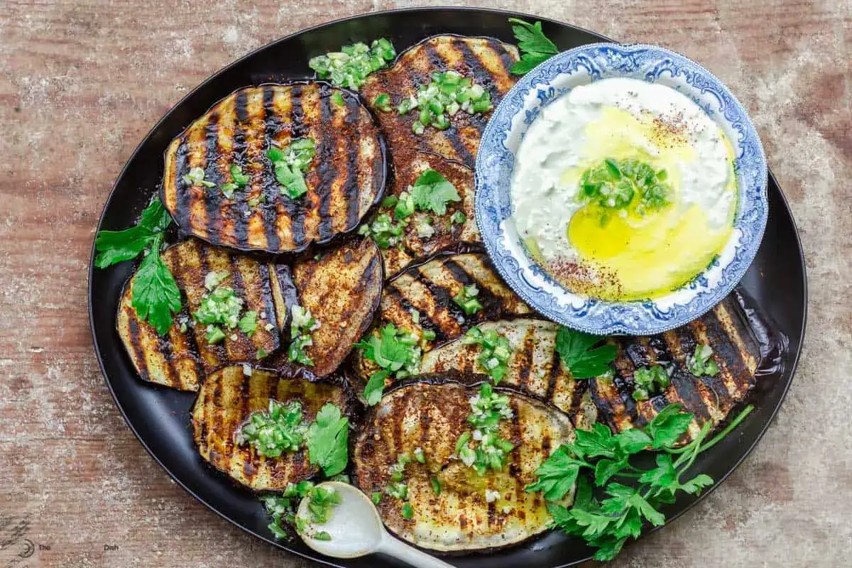 Gegrillte Aubergine-Scheiben mit Kr&auml;utern und einem Dip aus Joghurt und Oliven&ouml;l.