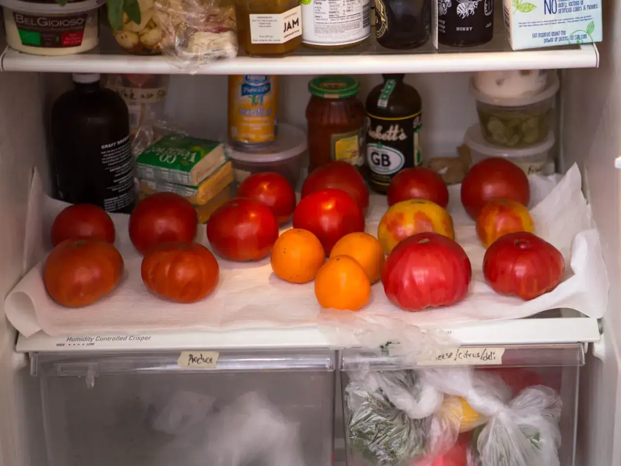 Frische Tomaten liegen auf K&uuml;chenpapier im K&uuml;hlschrank, bereit zum Einfrieren.