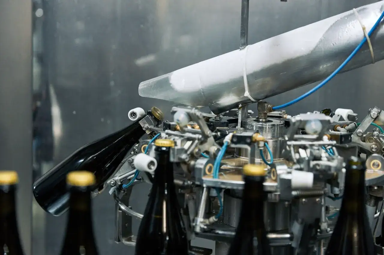Flaschen werden in einer Anlage für die méthode champenoise mit Kronkorken verschlossen.
