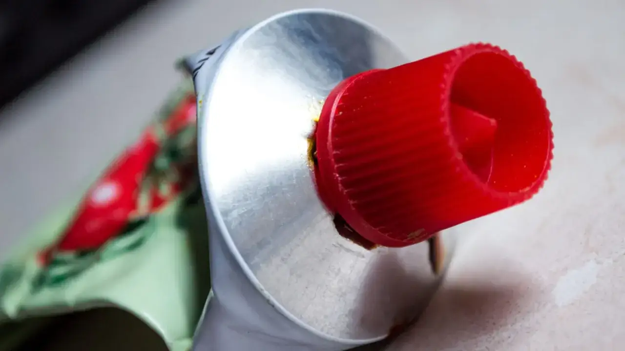 Nahaufnahme einer geöffneten Tube Tomatenmark mit rotem Deckel. Die Haltbarkeit von Tomatenmark ist wichtig für den Genuss.