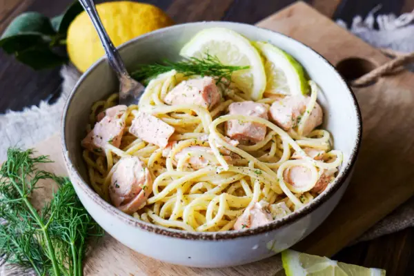 Eine Schüssel Pasta mit Lachs, garniert mit Dill und Zitronenscheiben. Ein köstliches Pasta Salmone Gericht.