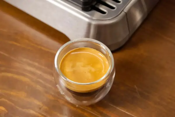 Ein frisch gebrühter Espresso Freddo in einem Glas auf Holztisch.